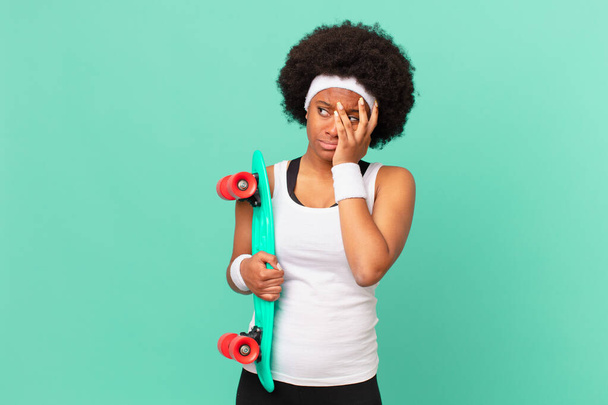 afro woman feeling bored, frustrated and sleepy after a tiresome, dull and tedious task, holding face with hand. skateboard concept - Photo, image