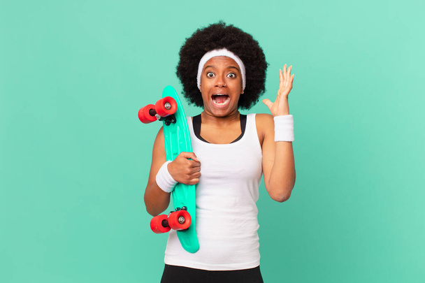 afro woman screaming with hands up in the air, feeling furious, frustrated, stressed and upset. skateboard concept - Foto, Imagen