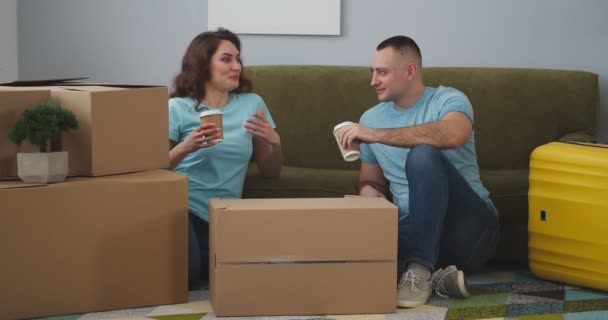 Счастливая молодая пара пьет кофе после переезда в новый дом - Кадры, видео