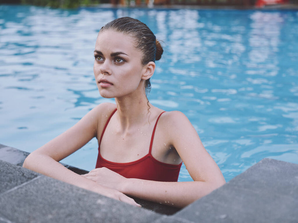 femme sexy en maillot de bain nage dans la piscine et se penche sur la tuile avec ses coudes - Photo, image