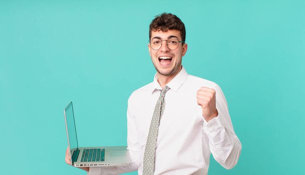 businessman with laptop feeling shocked, excited and happy, laughing and celebrating success, saying wow! - Fotografie, Obrázek