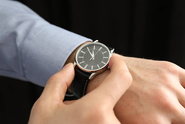 Man with luxury wrist watch on black background, closeup - Foto, afbeelding