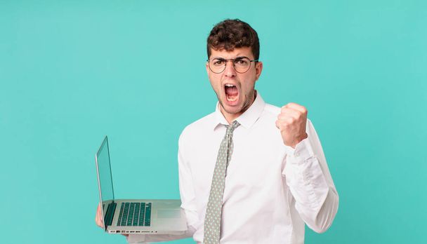 businessman with laptop shouting aggressively with an angry expression or with fists clenched celebrating success - Foto, afbeelding
