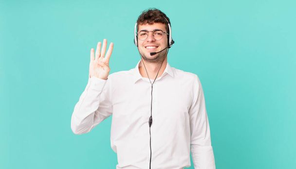 telemarketer smiling and looking friendly, showing number four or fourth with hand forward, counting down - Foto, afbeelding