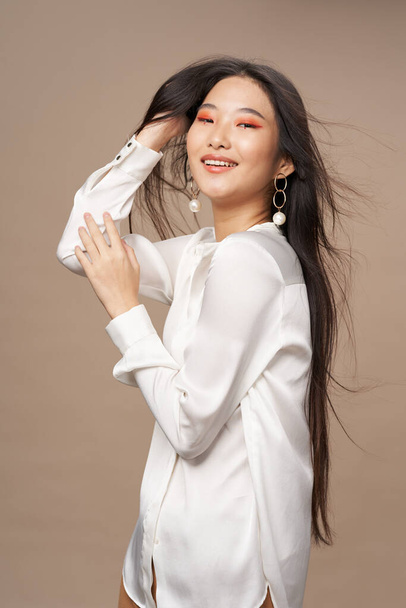 жінка азіатського вигляду яскравий макіяж біла сорочка бежевий фон розкіш
 - Фото, зображення