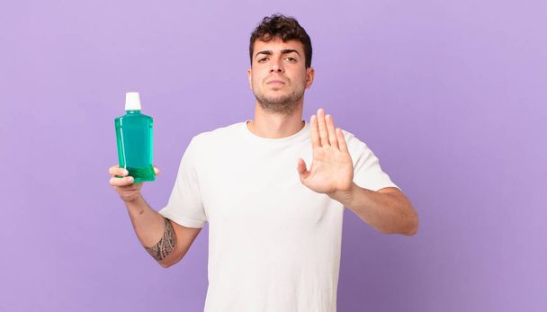 man with mouthwash looking serious, stern, displeased and angry showing open palm making stop gesture - Fotografie, Obrázek