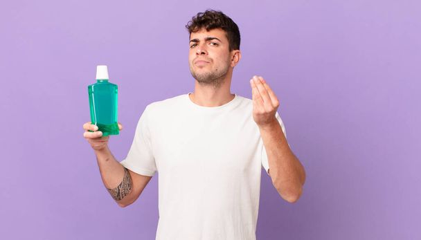 man with mouthwash making capice or money gesture, telling you to pay your debts! - Фото, зображення