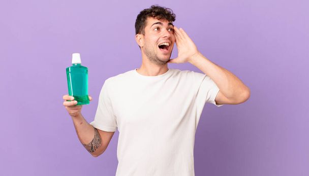 man with mouthwash feeling happy, excited and surprised, looking to the side with both hands on face - Φωτογραφία, εικόνα