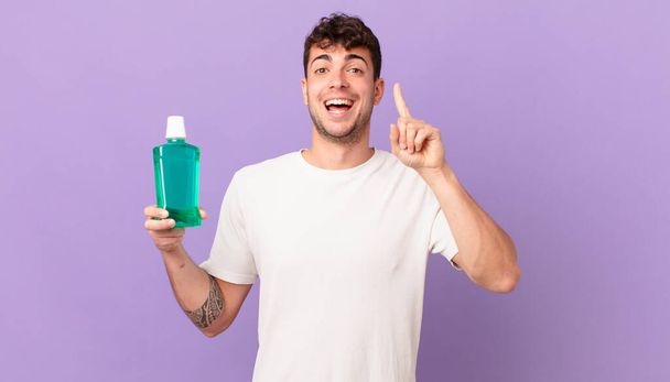 man with mouthwash feeling like a happy and excited genius after realizing an idea, cheerfully raising finger, eureka! - Zdjęcie, obraz