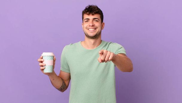 man with coffee pointing at camera with a satisfied, confident, friendly smile, choosing you - Fotoğraf, Görsel
