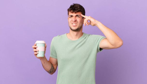 man with coffee feeling confused and puzzled, showing you are insane, crazy or out of your mind - Foto, imagen