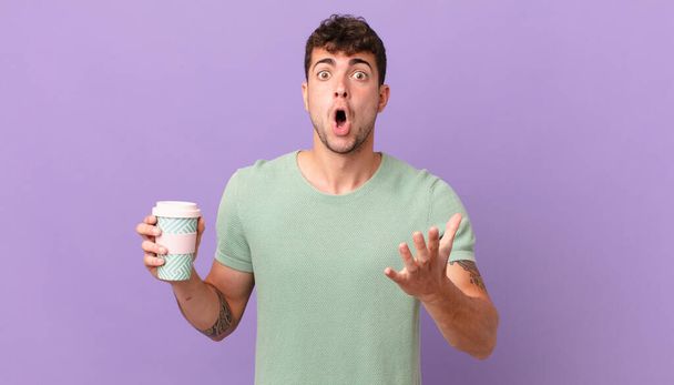 man with coffee open-mouthed and amazed, shocked and astonished with an unbelievable surprise - Photo, image