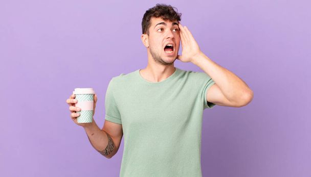 man with coffee feeling happy, excited and surprised, looking to the side with both hands on face - Foto, Imagem