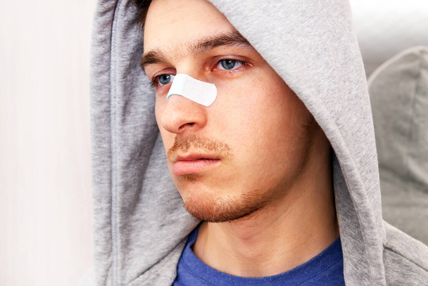 Sad Young Man with a Sticking Plaster on the Nose Portrait closeup - Fotoğraf, Görsel