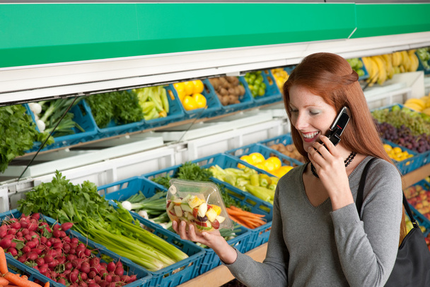 Grocery store shopping - Red hair woman with mobile phone buying fruit salad - Фото, изображение