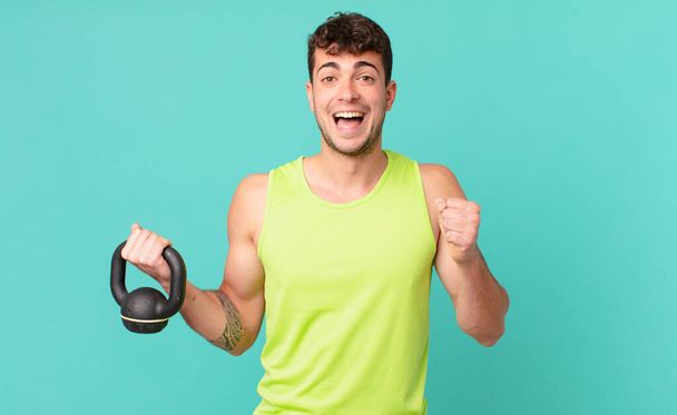 fitness man feeling shocked, excited and happy, laughing and celebrating success, saying wow! - Foto, Imagen
