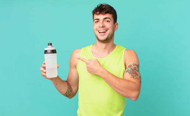 fitness man looking excited and surprised pointing to the side and upwards to copy space - Фото, изображение