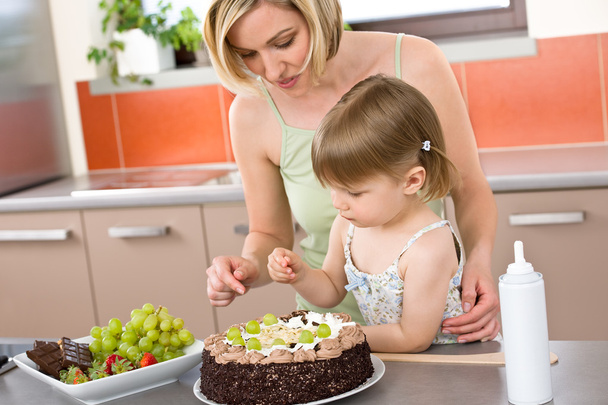 Mãe e criança com bolo de chocolate na cozinha
 - Foto, Imagem