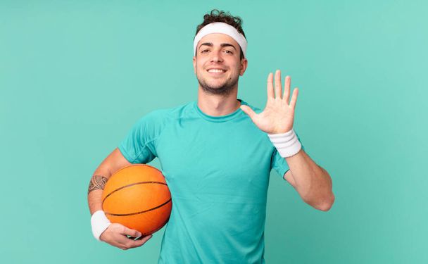 fitness man smiling and looking friendly, showing number five or fifth with hand forward, counting down - Foto, Imagen