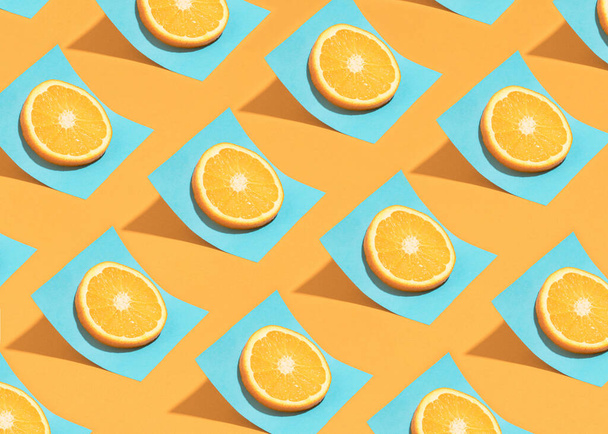 Patrón de verano de moda con rodajas de cítricos en una hoja de papel azul brillante sobre una mesa naranja soleada. Fondo mínimo de comidas orgánicas. - Foto, Imagen