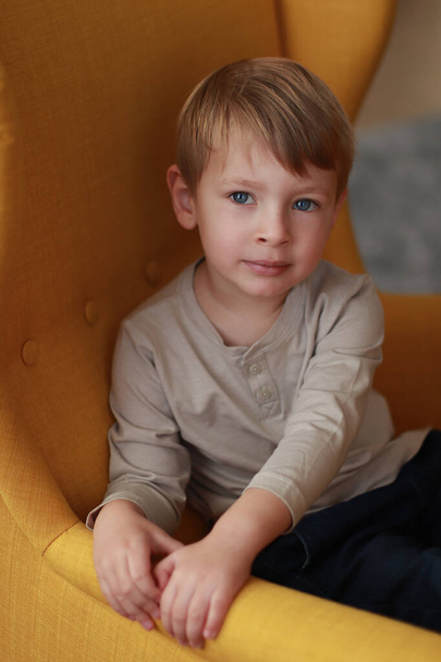 Petit garçon blond sur le fauteuil jaune. Journée internationale de l'enfance - Photo, image