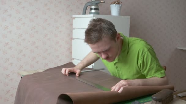 Young leather craftsman works at home, craftsman measures with a ruler to cut leather, leather goods business, tanner and leather working concept - Footage, Video