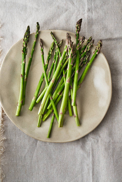Asparagus on a plate. Fresh asparagus on a fabric background. - Foto, afbeelding