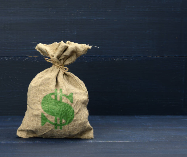 hnědá plátěná taška se symbolem dolaru na modrém pozadí. Koncepce úspor, půjček a investic. Finanční pomoc - Fotografie, Obrázek