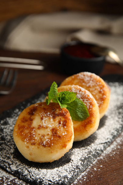Delicious cottage cheese pancakes with mint and icing sugar on wooden table - Foto, Imagen