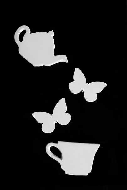 Білий чайник і чашка, білі метелики. чорний вінтажний фон. Сервіс для ляльок
 - Фото, зображення