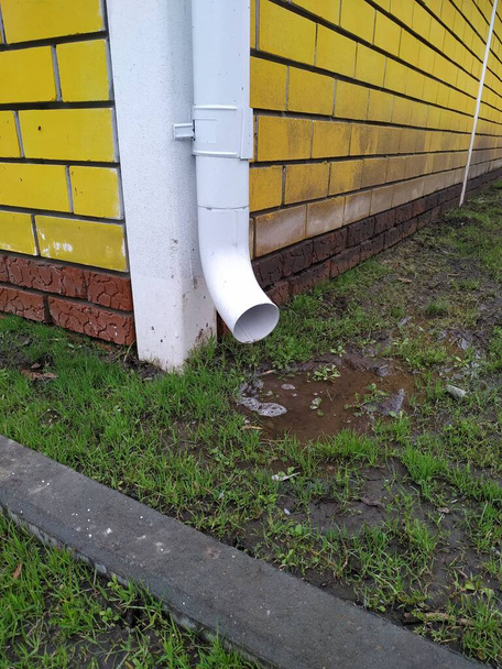 Bajamar en una casa de campo. Una tubería de drenaje en una casa de campo en una pared de ladrillo amarillo. - Foto, imagen