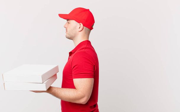 Pizza-Lieferant Mann auf Profil-Ansicht sucht Raum vor kopieren, Denken, Vorstellen oder Tagträumen - Foto, Bild