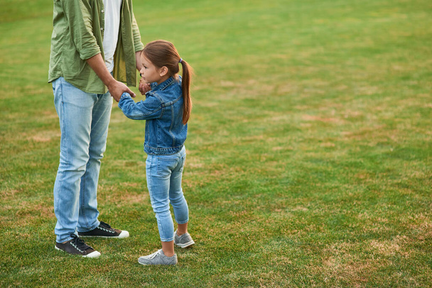 Carina bambina che passa del tempo con suo padre, giocando, divertendosi nel bellissimo parco verde in una giornata estiva - Foto, immagini