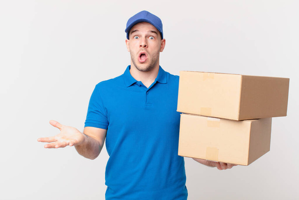 package deliver man open-mouthed and amazed, shocked and astonished with an unbelievable surprise - Fotoğraf, Görsel