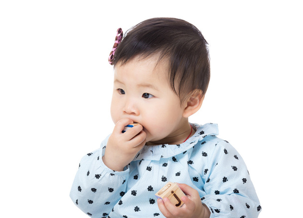 asia baby girl steckte hölzernen spielzeugblock in den mund - Foto, Bild