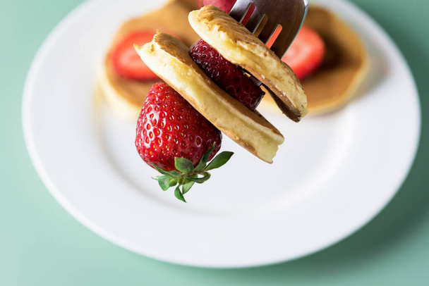 Freshly Baked American Mini Pancakes on a Fork With Fresh Berry Tasty Breakfast Green Background Close Up - Valokuva, kuva