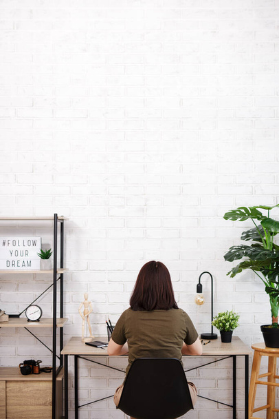 Задний вид женщины, сидящей в офисе с копировальным местом на стене - Фото, изображение