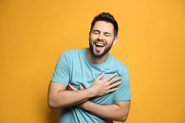Young man laughing on yellow background. Funny joke - Foto, Imagen