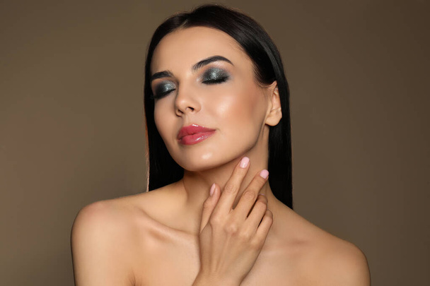 Beautiful young woman with evening makeup on brown background. Eye shadow product - Φωτογραφία, εικόνα