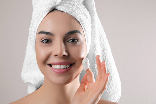 Woman using silkworm cocoon in skin care routine on light grey background. Space for text - Foto, afbeelding