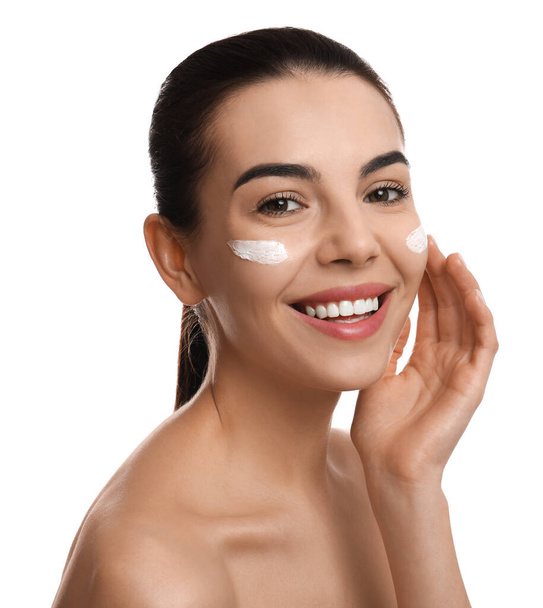 Young woman applying facial cream on white background - Foto, Bild