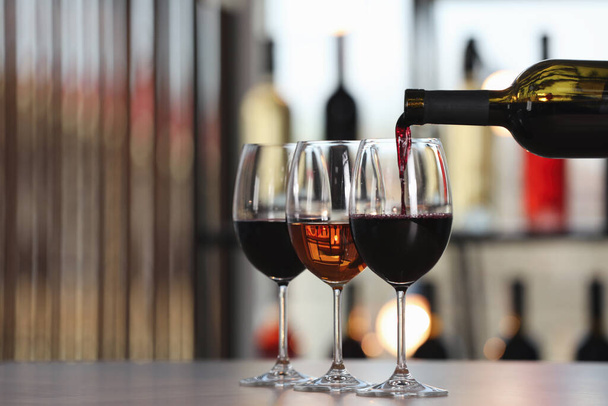 Наливаючи червоне вино з пляшки на склянку в приміщенні, місце для тексту
 - Фото, зображення