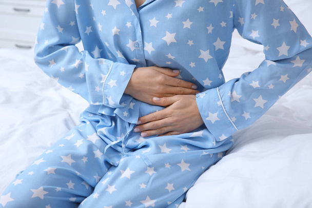 Young woman suffering from stomach ache on bed, closeup - Photo, image