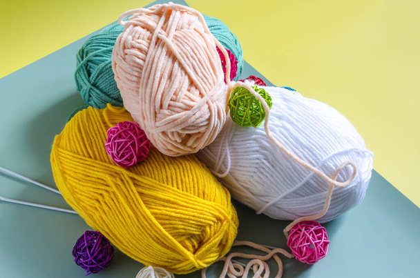 Skeins of multicolored yarn on a two-tone yellow-green background close-up from above. Yarn for knitting. - 写真・画像