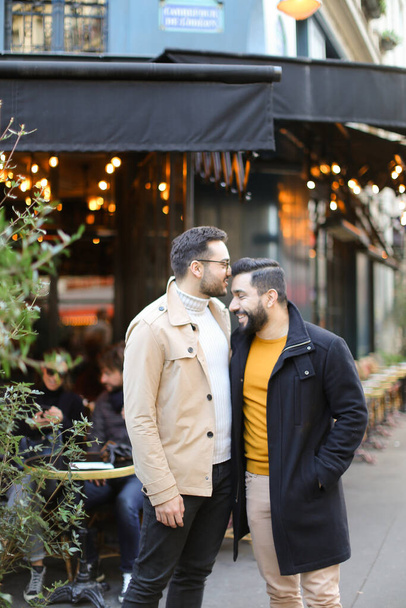 Deux gays heureux debout près d'un café de rue et câlins . - Photo, image