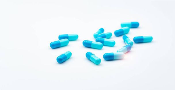 Синие антибиотики капсулы таблетки распространяются на белом фоне. Устойчивость к антибиотикам. Фармацевтическая промышленность. Здравоохранение и медицина. Концепция бюджета здравоохранения. Капсульная промышленность. - Фото, изображение