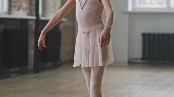 Tilt up πλάνο του κομψό καυκάσιος 9-year-old μπαλαρίνα σε ανοιχτό ροζ φόρεμα ποζάρουν στην κάμερα στέκεται στις μύτες των ποδιών της σε pointe παπούτσια εξάσκηση μπαλέτο χορό - Πλάνα, βίντεο