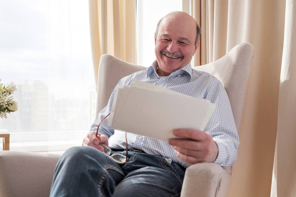Senior man wathcing photos of his family smiling - Photo, Image
