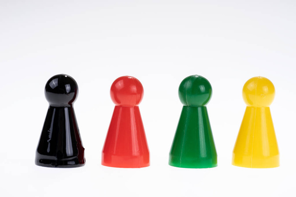 Figure di gioco di plastica in nero, rosso, verde e giallo su sfondo bianco - Foto, immagini