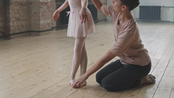 Kallista kuvaa pikkutytöstä, joka opettelee tanssimaan balettia tanssistudiossa harjoittelevan naisvalmentajansa avulla. - Materiaali, video